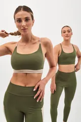 Top deportivo color beige con contorno inferior y tiras cruzadas en la espalda color borgoña. Cuenta con almohadillas removibles.