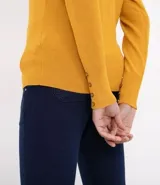 Cardigan de punto color mostaza con escote en V y cierre frontal de botones. Presenta mangas largas y diseño ajustado al cuerpo.