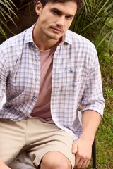 Camisa de lino con diseño a cuadros en tonos celestes y rosados, de manga larga, con cuello camisero, cierre frontal de botones y un bolsillo aplicado en el pecho con logo bordado.