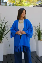 Saco abierto de punto color azul vibrante, con mangas tres cuartos y detalle de flecos largos en el ruedo.