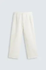 Pantalón de corte relajado confeccionado en tejido de cáñamo color blanco roto. Presenta cintura elástica con cordón interior ajustable, cierre frontal con botones, bolsillos laterales y un bolsillo trasero de plastrón.
