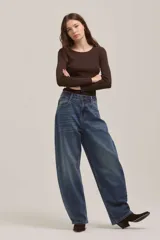 Jean de corte wide leg y tiro alto, con diseño de pierna curva o tipo barril, en tono azul medio con efecto lavado.