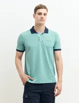 Remera manga corta color verde con cuello polo y bolsillo en el pecho. El cuello y los puños son de color azul marino.