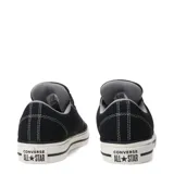Championes Converse Chuck Taylor de corte bajo, color negro con costuras blancas contrastantes. Presentan ojales superiores en azul y suela de goma blanca con doble línea negra.