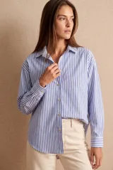 Camisa oversize de algodón con estampado de rayas verticales celestes y blancas, cuello clásico y mangas largas con puños abotonados.