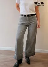 Jeans palazzo de corte ancho, color gris, tiro medio y botamanga con dobladillo ancho fijo. Incluye cinto negro con hebilla metálica.