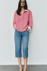 Camisa de rayas finas color rosado, con cuello solapa y puños largos en color blanco a contraste. Presenta cierre frontal con botones y bajo asimétrico con aberturas laterales.