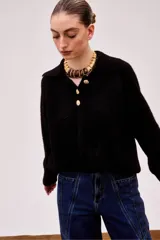 Sweater negro de alpaca con cuello polo, manga larga y cierre frontal con tres botones dorados.