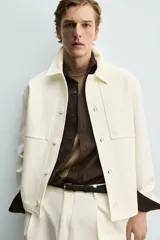Sobrecamisa marrón de corte boxy fit en tejido compacto, con cuello solapa, manga larga con puños abotonados, bolsillos frontales de parche y cierre central de botones.