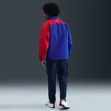 Campera deportiva Nike del Paris Saint-Germain, modelo Total 90 Reissue 2004, de color azul con una de las mangas en color rojo. Cuenta con cierre frontal completo, cuello alto y bolsillos laterales.
