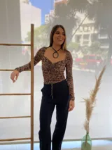 Pantalón negro de vestir, de corte recto, con bolsillos laterales y traseros. Se ajusta a la cintura con cinturón de cuero marrón.