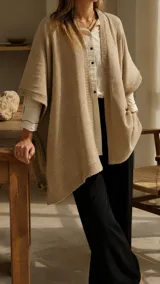 Ruana de hilo de algodón color beige, de diseño amplio y liviano con terminaciones tejidas en los bordes y costados abiertos.