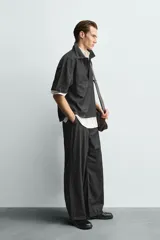 Camisa de manga corta con cuello solapa y cierre frontal de botones. Confeccionada en tejido denim de algodón, de corte relajado y aberturas laterales en el bajo.