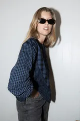 Blusa de algodón con estampado a cuadros en tonos azul y negro, con bordados decorativos en color bordó sobre el canesú. Presenta cierre frontal con botones, cuello redondo y mangas largas levemente abullonadas.