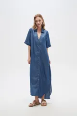 Vestido largo tipo camisero de lyocell, con cuello camisero, cierre frontal de botones, mangas cortas con dobladillo y bolsillos laterales. Presenta un corte holgado y tajos laterales en el ruedo.