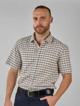 Camisa de manga corta con cuello camisero y botones frontales. El tejido es de color crema con un patrón de cuadros pequeños en negro y marrón.