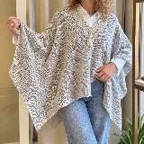 Ruana tejida de punto en color gris, con diseño amplio y envolvente, escote en V y delicados detalles bordados a mano con perlas y abalorios alrededor del cuello.