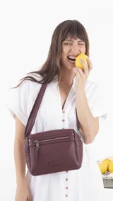 Bandolera color beige de símil cuero, con cierre principal, bolsillos interiores, bolsillo frontal y posterior con cierres, y bolsillos laterales. Incluye correa extensible.