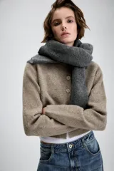 Chaqueta de punto suave en color beige melange, con cuello redondo, manga larga y cierre frontal de botones.