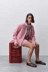 Camisa de calce relajado y silueta amplia con estampado cuadrillé en tonos rojo y blanco. Presenta cuello clásico, cierre frontal mediante botones y mangas largas.