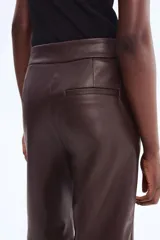 Pantalón de tejido revestido color marrón oscuro, de corte recto y tiro alto, con pretina prolongada y cierre frontal.