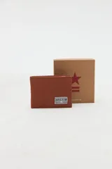 Billetera de canvas de algodón color marrón, con compartimentos internos y detalle de etiqueta bordada con el logo "Uniform Social Club" en el frente.