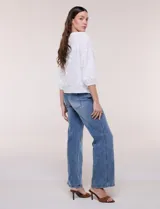 Blusa blanca de calce holgado, con bordado en relieve tipo broderie de motivos florales en toda la prenda. Presenta escote en V con fruncido en los hombros, cierre frontal con botonadura y mangas tres cuartos abullonadas con puños elastizados.