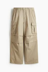 Pantalón cargo de algodón color beige, con corte holgado y diseño amplio. Cuenta con bolsillos laterales de fuelle y pliegues en las rodillas.