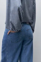 Jeans wide leg de tiro alto y pierna amplia, en lavado clásico, con bolsillos delanteros y traseros, cierre frontal con botón y presillas para cinturón.