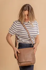 Bandolera de diseño simple con tapa frontal, confeccionada en material símil cuero. Cuenta con correa ajustable, división interna y bolsillos internos para mayor organización.