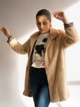 Tapado negro de piel sintética con cuello solapa y mangas largas. El forro interior de las mangas tiene un estampado animal print.