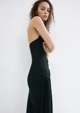 Vestido largo negro de corte slim, con cuello drapeado, sin mangas y detalle de fruncido lateral con caída de tela en la cadera.