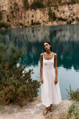 Sandalia plana color marrón con tiras cruzadas y detalle metálico dorado en la parte delantera.