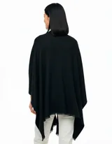 Ruana de tejido soft color negro, con cuello en V y un nudo o pasador frontal que ajusta la prenda. Los bordes tienen terminación desflecada.
