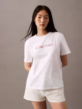 Remera blanca de manga corta con cuello redondo y corte regular. Presenta el logo de Calvin Klein estampado en el pecho con un efecto degradado de colores que va del rosado al cobre.