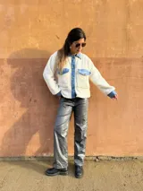 Chaqueta color crema de corderito con detalles en jean azul en cuello, solapa, bolsillos y puños.