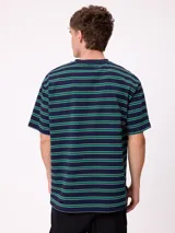 Remera de corte holgado con diseño de rayas horizontales en tonos beige, marrón y azul claro. Presenta cuello redondo, mangas cortas y un bolsillo frontal en el pecho con el logo de la marca bordado.