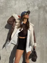 Campera tipo gamulán color marrón con interior y solapas de corderito sintético en color crema. Presenta cierre frontal, bolsillos laterales y diseño de corte holgado.