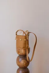 Cartera tipo canasta de cuero con estampado animal print de vaca en blanco y negro. Tiene correa larga de cuero negra y herrajes metálicos plateados.