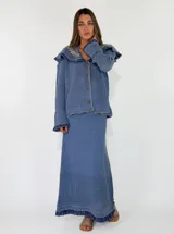 Saco tejido de punto color azul con diseño calado, cuello grande con bordados florales en tono crudo, volados decorativos y cierre frontal con un botón.