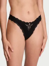 Panty tipo colaless de microfibra negra con detalles de encaje en los bordes y un aplique de encaje transparente en el centro delantero con un detalle de roseta decorativa.
