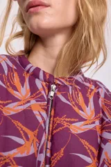 Campera bomber corta color bordó con estampado abstracto en tonos naranja y lila, cierre frontal y mangas largas abullonadas.