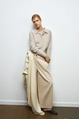 Jersey de lana 100% color beige, con cuello polo, manga larga y botones delanteros.