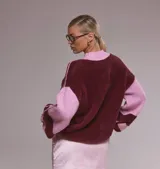Sweater oversize de punto suave en combinación bicolor bordó y rosa, con cuello redondo tejido y estampa frontal con la palabra Darling en tipografía cursiva.
