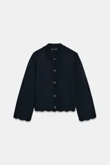 Chaqueta de punto color azul marino, con cuello solapa, manga larga y cierre frontal con botones metálicos. Presenta terminaciones en ondas en el bajo y los puños.