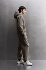 Pantalón jogger de entrenamiento, corte regular fit, color verde oliva oscuro. Confeccionado en tejido técnico compacto de algodón con elasticidad y efecto neopreno. Presenta cintura elástica ajustable con cordón blanco, bolsillos frontales y un bolsillo lateral con cierre de cremallera. El bajo termina en puño.