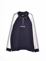 Buzo de media cremallera con cuello polo, diseño de bloques de color en azul marino, blanco y gris, con estampado frontal y puños elásticos.