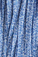 Vestido corto azul con estampado floral blanco, escote en V pronunciado con fruncido central, mangas globo largas con lazos ajustables en los puños y falda corta plisada.