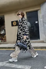 Tapado de corte recto y largo midi con estampado animal print de manchas grandes en tonos beige y negro. Presenta solapas clásicas, cierre frontal con botones y mangas largas.