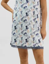 Camisón corto de tejido soft, color blanco con estampado floral y de hojas en tonos azules y marrones. Cuenta con mangas cortas y escote en V con terminaciones de encaje azul en el cuello, las mangas y el ruedo.